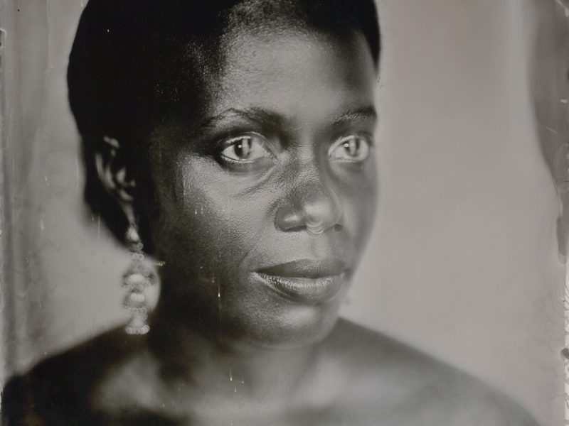 A black and white portrait of a figure looking in the distance with lights dancing in their eyes
