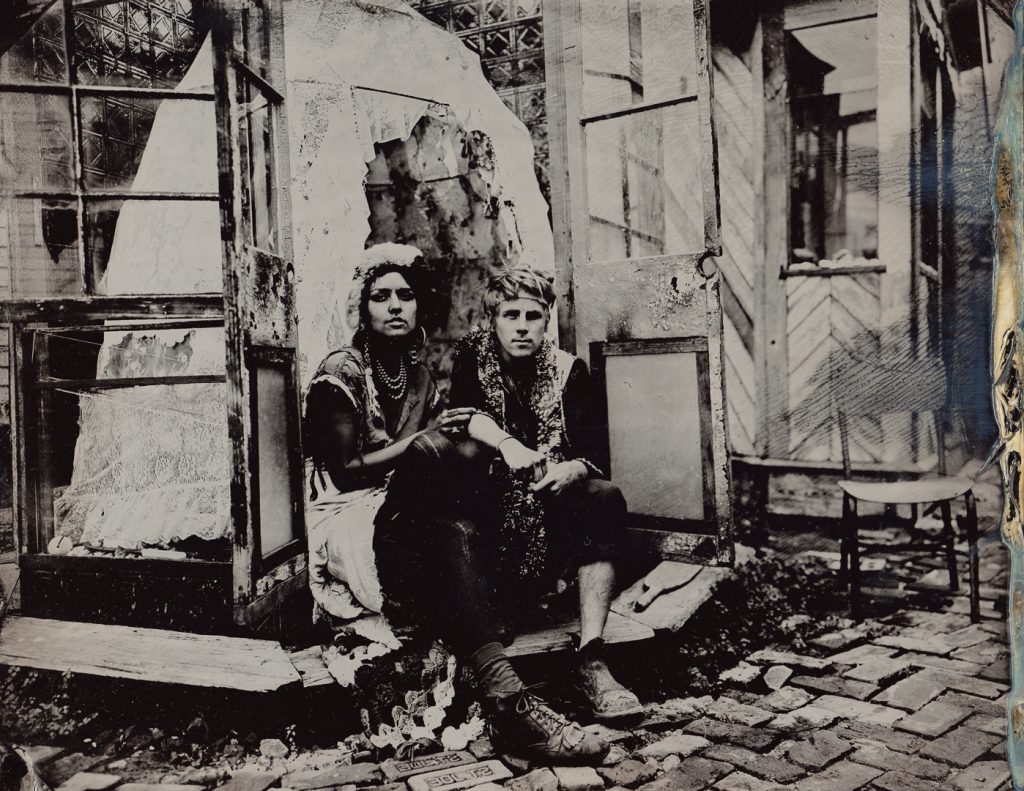 Two people sitting in a glass doorway infront of a lace bell