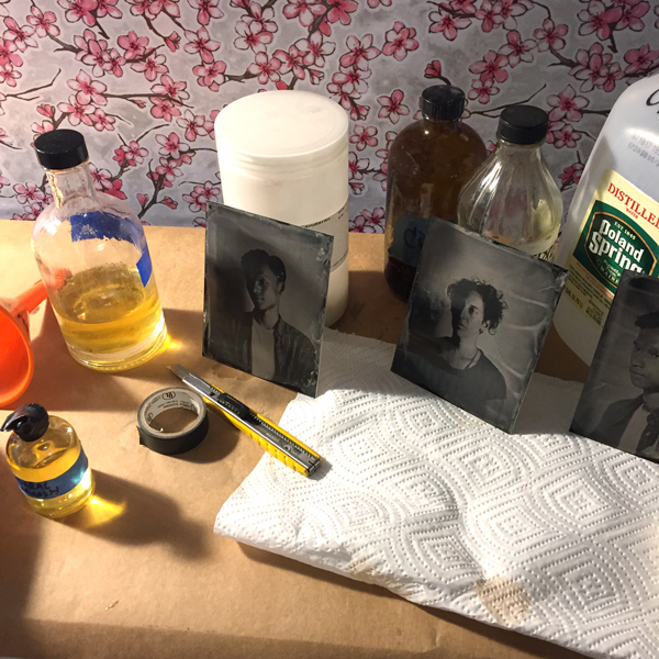 Tintype photographs lean against bottles of varnish and developer in the studio