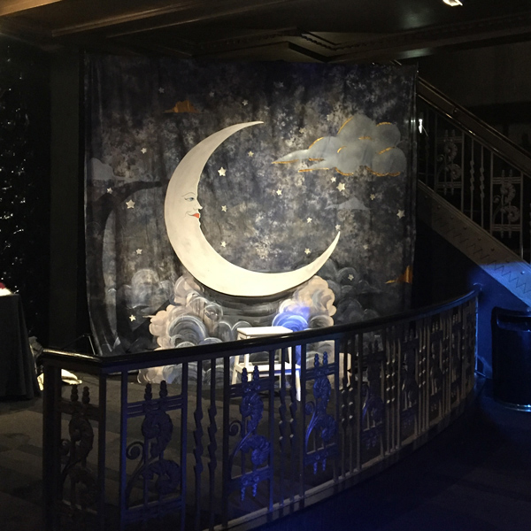 A paper moon photo set and backdrop are illuminated behind a luxurious banister