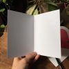 The interior of a blank notecard infront of a plant and wood table